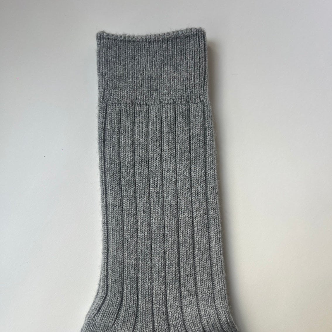 A pair of heather grey, ribbed, thickly knit merino socks. Made in Italy.