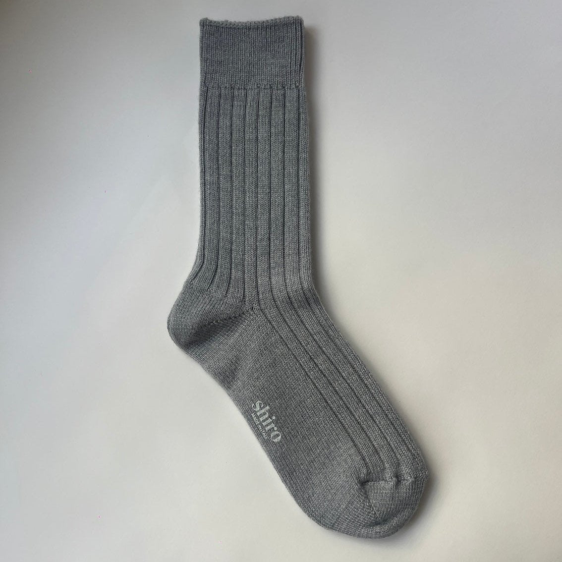 A pair of heather grey, ribbed, thickly knit merino socks. Made in Italy.